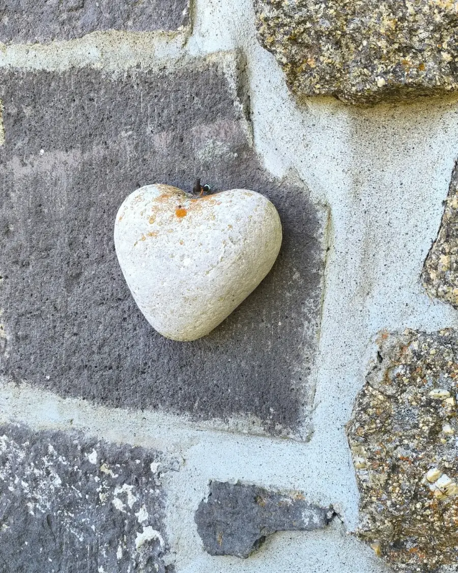 Un cœur en pierre blanche posé sur un vieux mur
