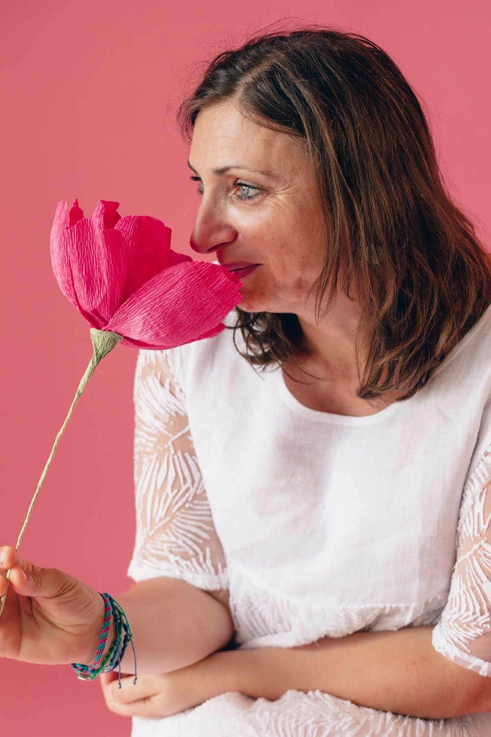 Sandrine Garcia souriante, une fleur rose en papier à la main