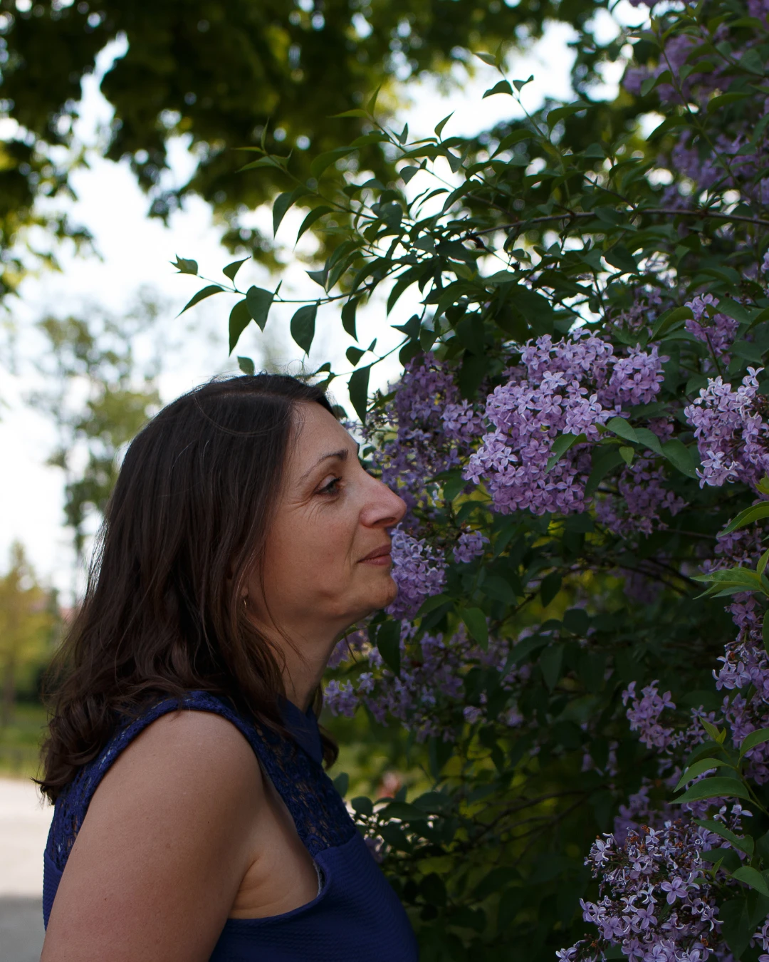 Sandrine Garcia de profil, respirant les fleurs d'un lilas