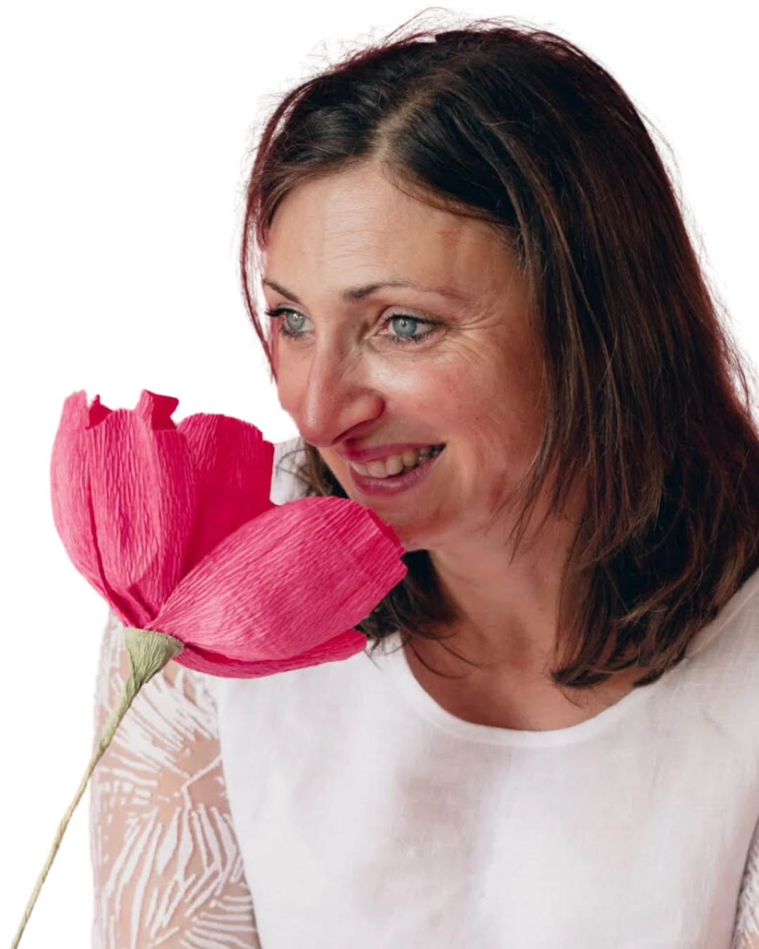 Sandrine Garcia souriante, respirant une grande fleur rose en papier