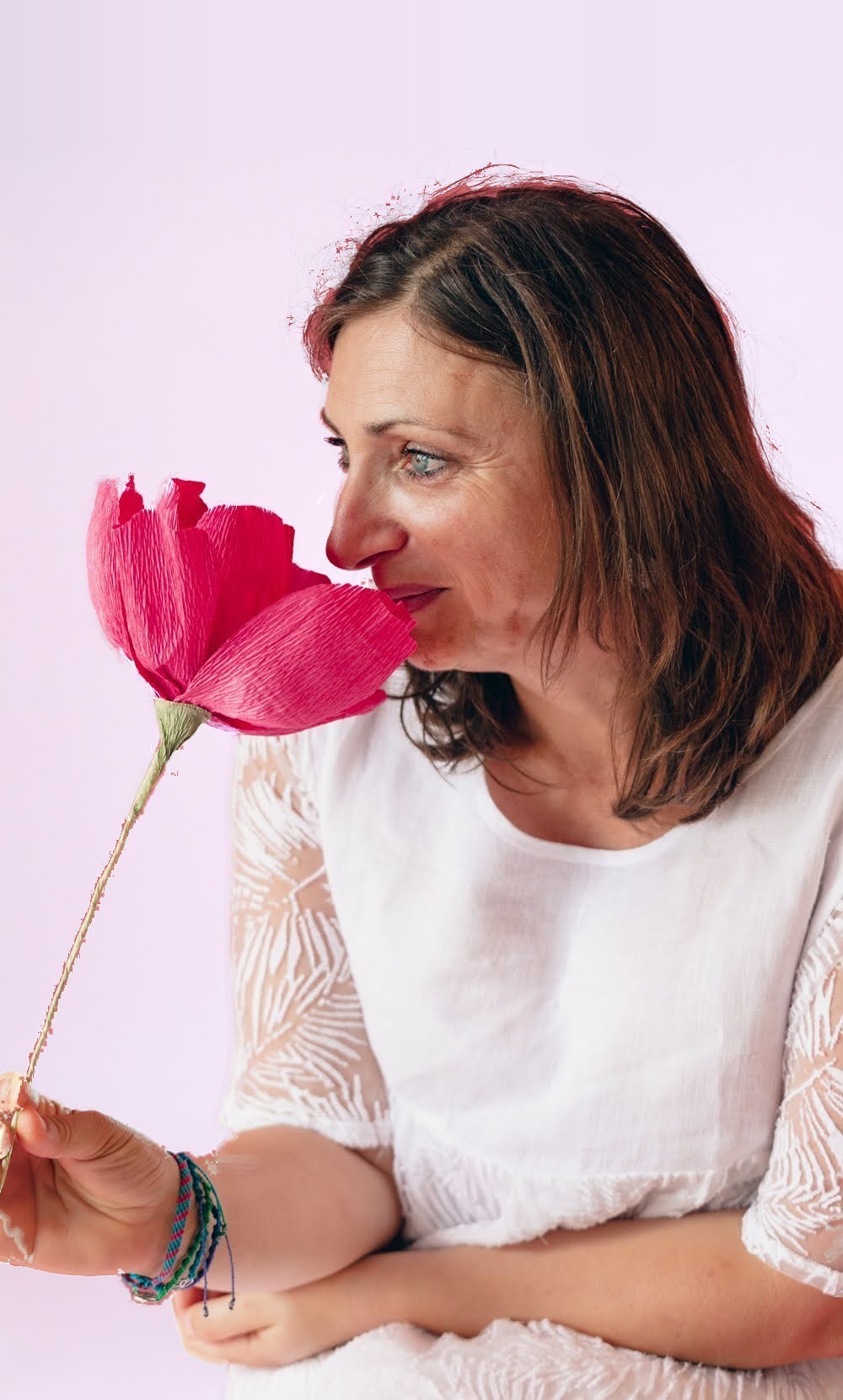 Sandrine Garcia de profil, respirant une grande fleur rose en papier