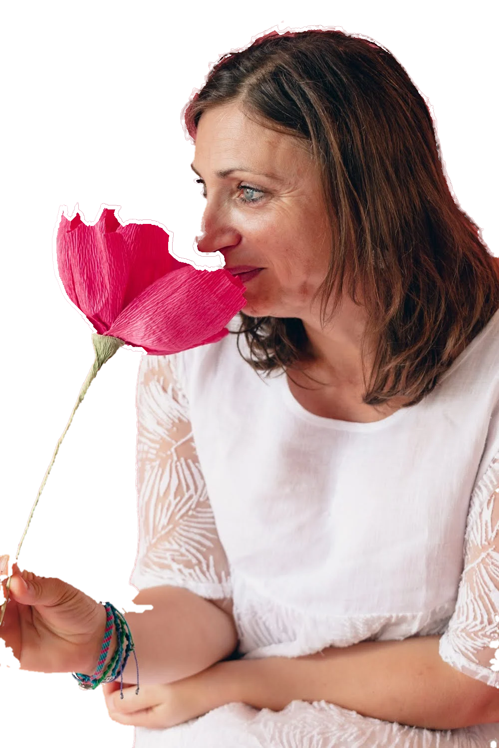 Sandrine Garcia, en blouse blanche, respire une grande fleur rose en papier